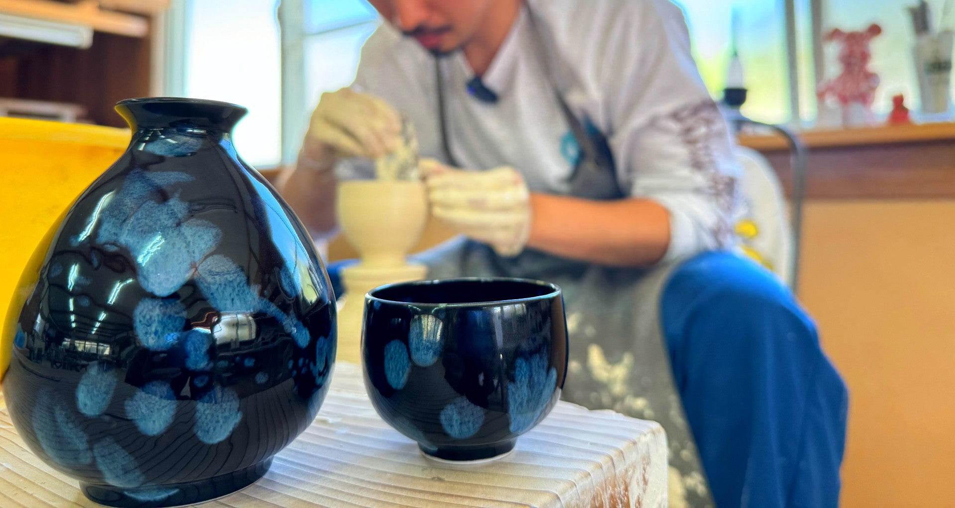 Two potteries in front of a man making pottery