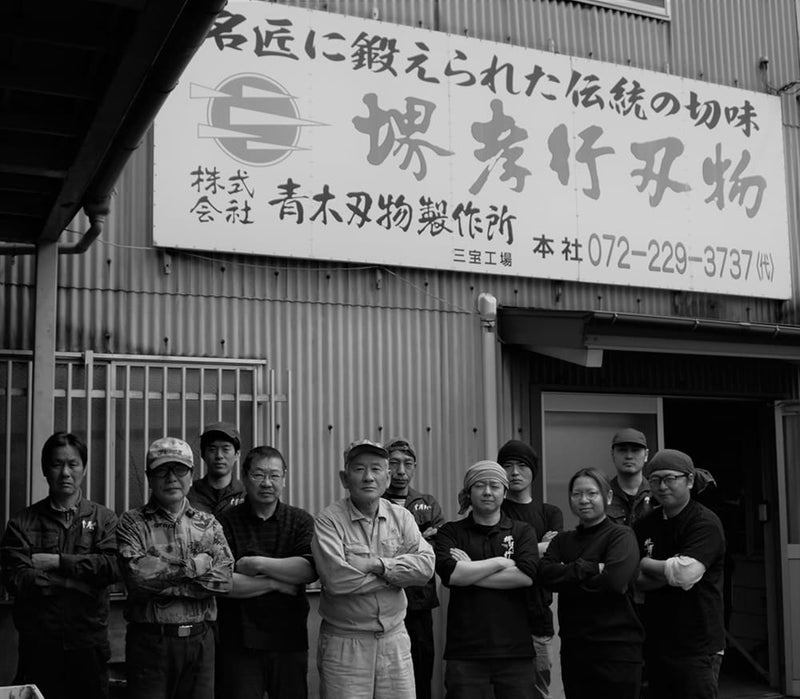 The whole team of craftsmen that make Sakai TAKAYUKI for Aoki Hamono in front of the entrance of the workshop
