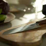NAGOMI Santoku Knife 180mm crafted by Mitsuboshi Cutlery on a wooden cutting board