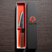 Nishida Hamono Polish Petty Knife 100mm in an open box next to the cover with the Japanese character Nishida Hamono logo