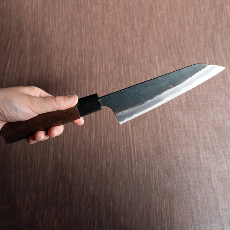 Hand holding a Nishida Hamono Kurouchi Gyuto Knife 165mm