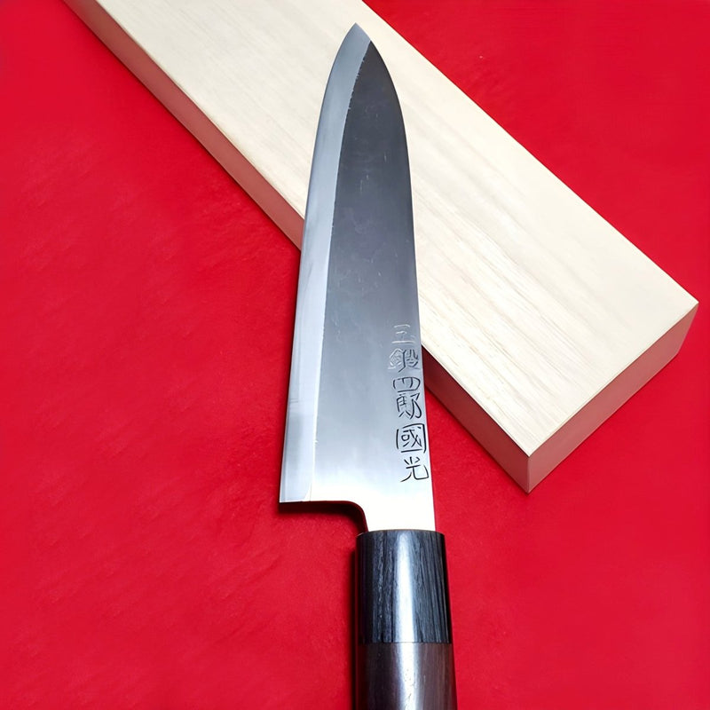 Tamahagane 21cm Gyuto Knife by Shirou Kunimitsu on red background and light wood 