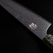 Closeup of back engraving on the blade of Omoi Gyuto stainless steel Kitchen Knife 180mm crafted by Nenohi Cutlery on black background 