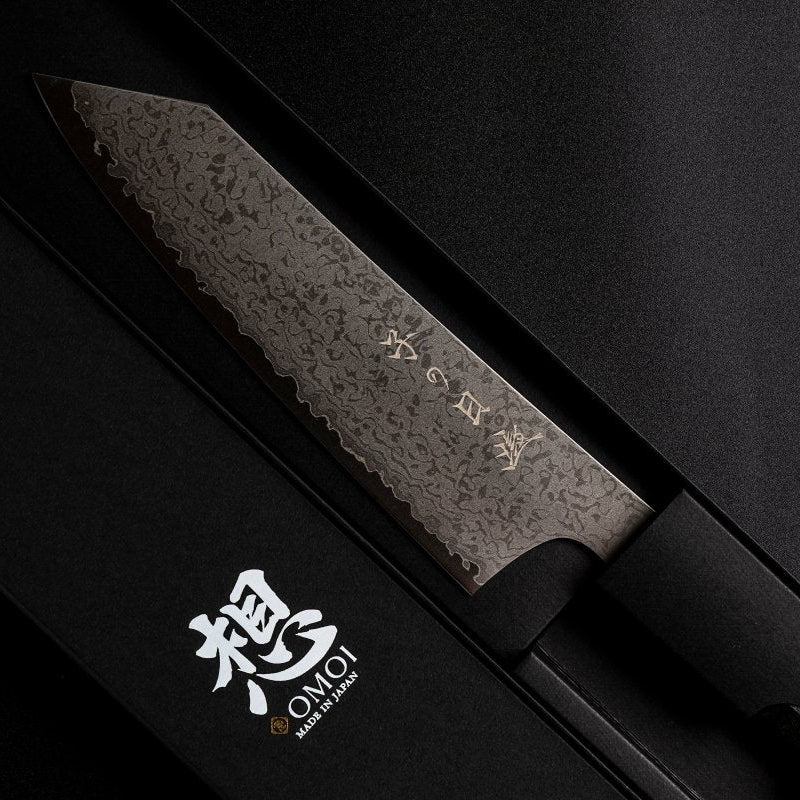 Omoi Kiritsuke Santoku Kitchen Knife 180mm by Nenohi Cutlery in box next to box cover which reads Omoi Made in Japan zoomed in
