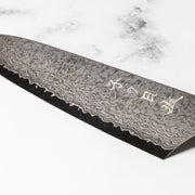 Closeup of front engraving on the blade of Omoi Gyuto stainless steel Kitchen Knife 180mm crafted by Nenohi Cutlery on white background 