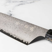 Closeup on blade of Omoi Santoku Kitchen Knife 180mm crafted by Nenohi Cutlery on white background