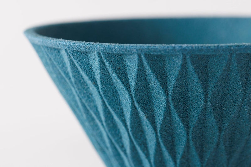 Closeup on upper edge of blue COFIL Flow Ceramic Coffee Filter on white background