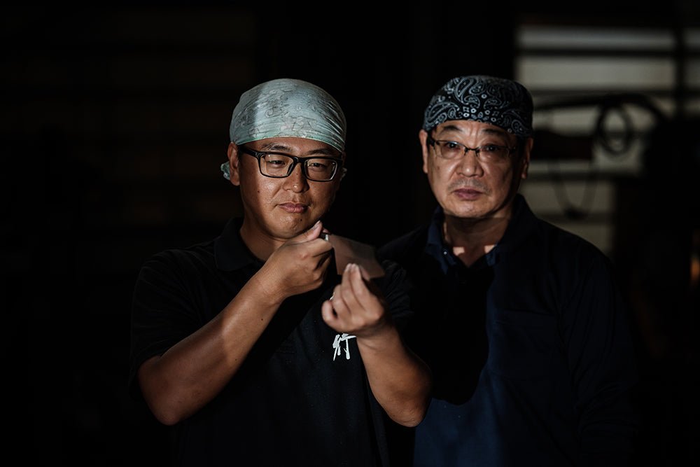 Two craftsmen from Aoki Hamono inspecting the balde of a Sakai TAKAYUKI Stainless Steel knife