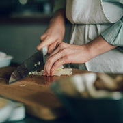 Closeup of woman hands using the KISEKI Satnoku knife to cut vegetables in the kitchen
