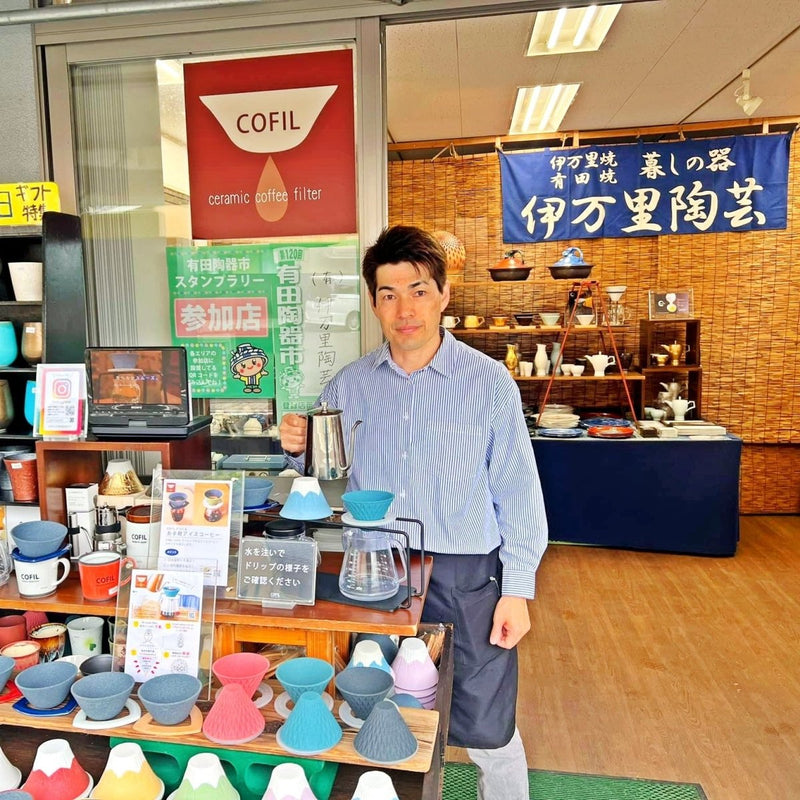 Artisan of Imari Togei in from of their store and behind a shelf full of COFIL ceramic coffee filters