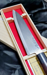 Closeup on blade of Tamahagane 21cm Gyuto Knife by Shirou Kunimitsu in light wooden box with red lining