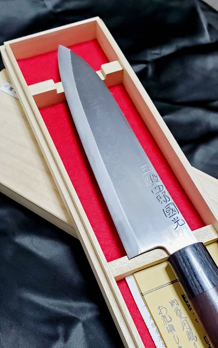 Closeup on blade of Tamahagane 21cm Gyuto Knife by Shirou Kunimitsu in light wooden box with red lining
