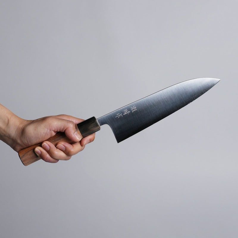 Hand holding Sakoda Hamono Polished Aogami Super Gyuto 180mm on grey background