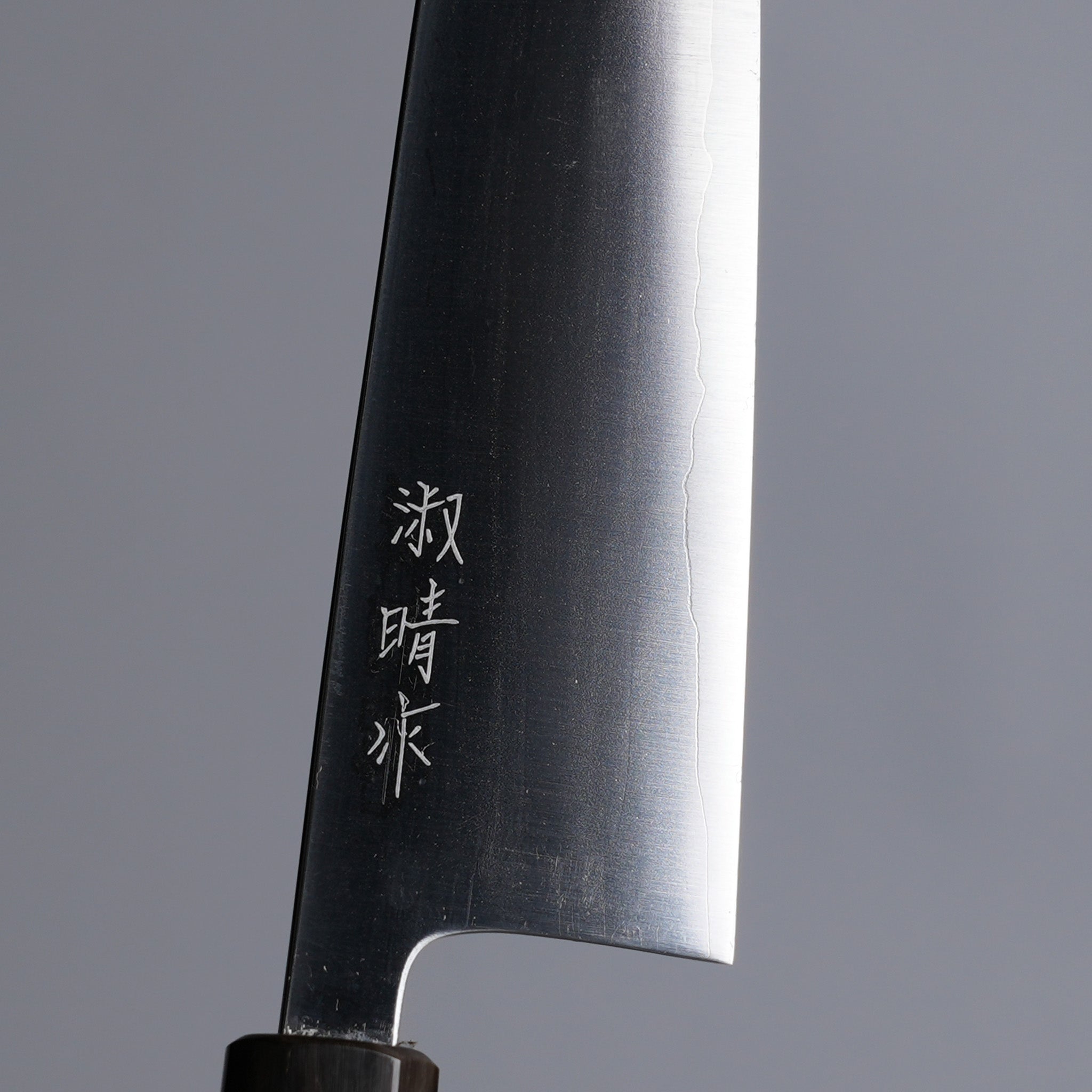 Closeup on engraving on Sakoda Hamono Polished Aogami Super Gyuto 180mm on grey background