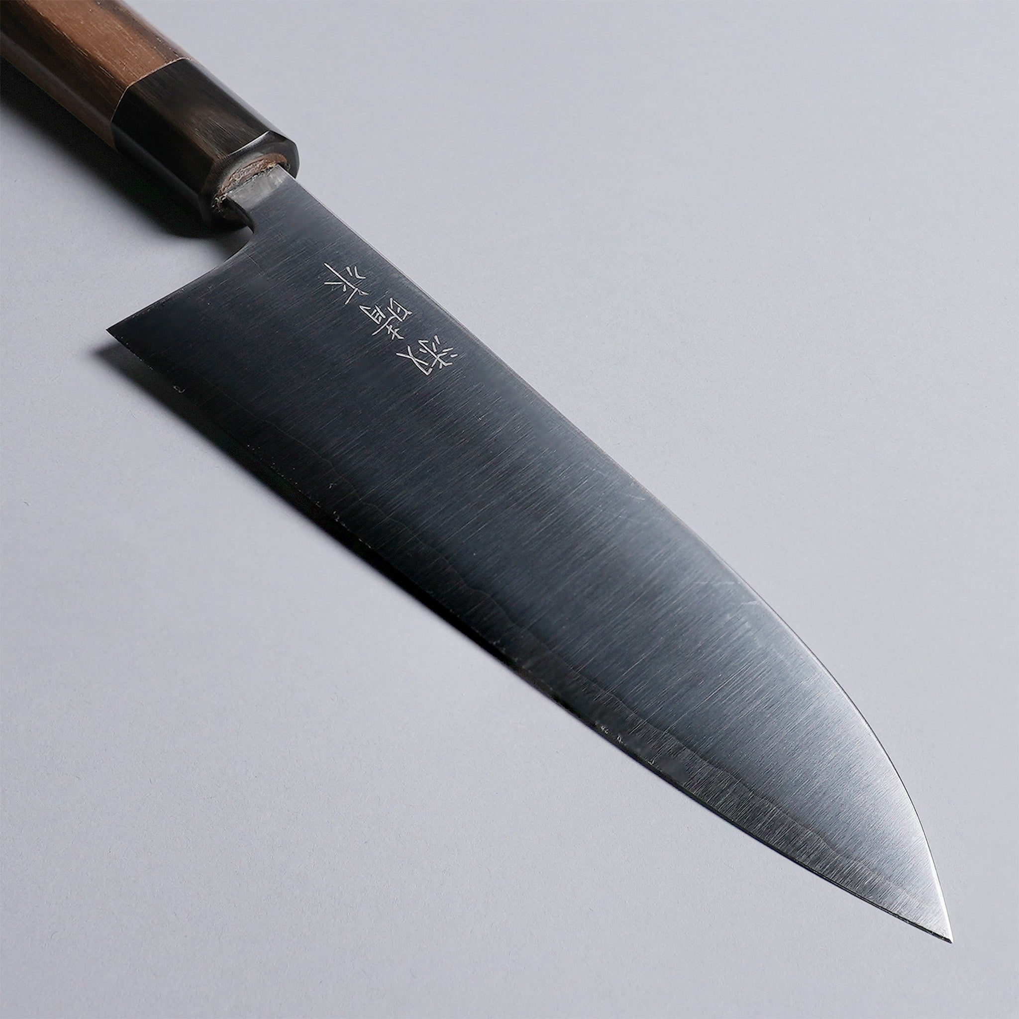 Closeup on tip of Sakoda Hamono Polished Aogami Super Gyuto 180mm on grey background