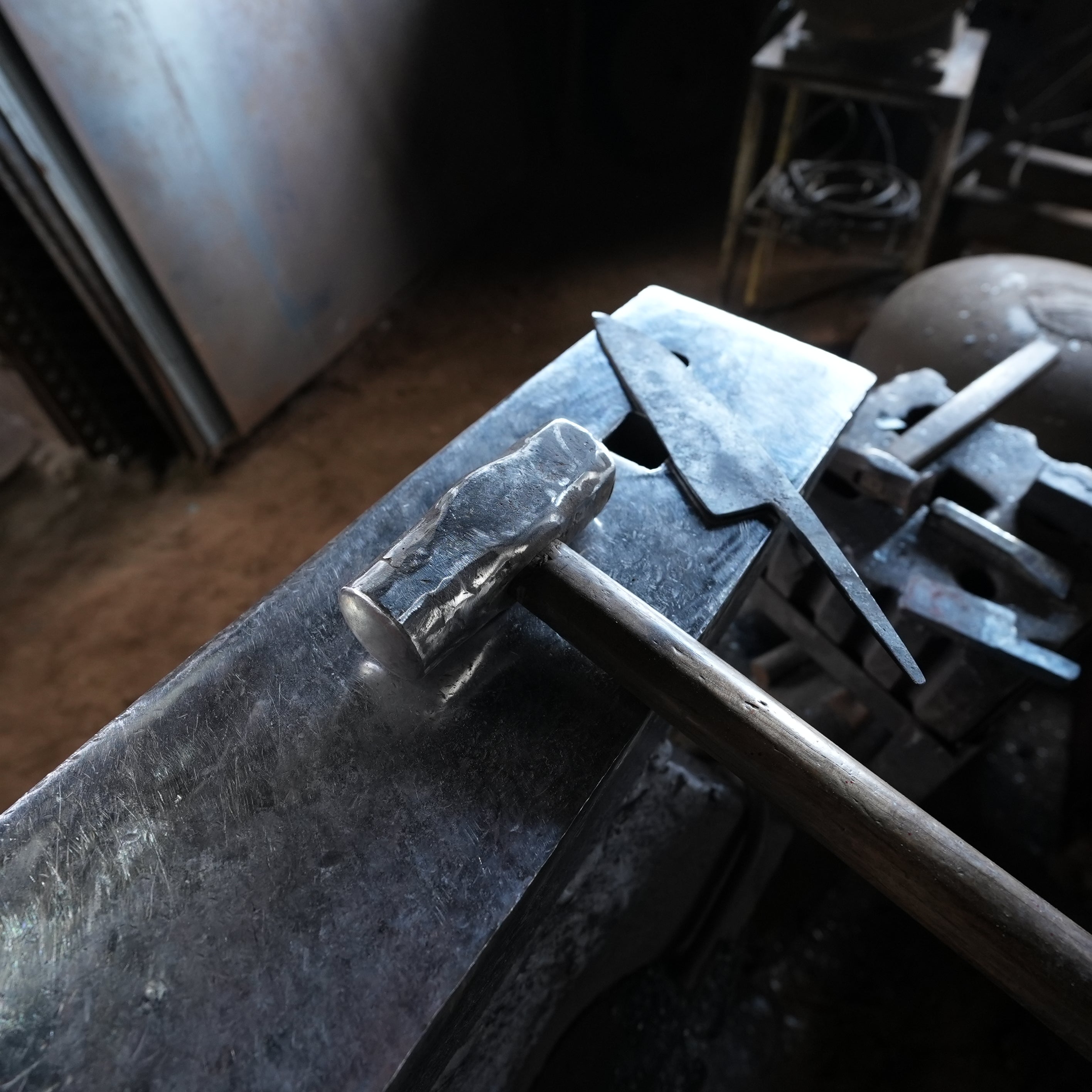Hammer and metal balde closeup on the anvil inside the Kabayama Blacksmith workshop