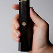 Closeup of the decorative motif of a handheld ebony wood handle for a Shirou Kunimitsu Special White Steel Kurouchi Santoku Knife 170mm with a decorative motif.