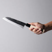Hand holding Minomo Blacksmith Santoku Knife 165mm on grey background