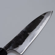 Closeup on blade of Kurouchi Santoku Knife 165mm crafted by Nakamura Blacksmith displayed diagonally on grey background