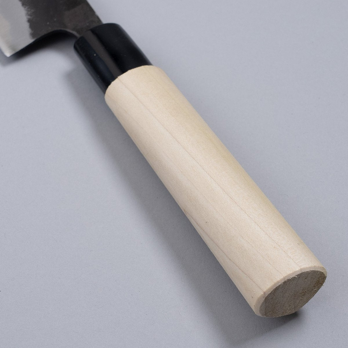 Closeup on handle of Kurouchi Santoku Knife 180mm crafted by Nakamura Blacksmith on grey background