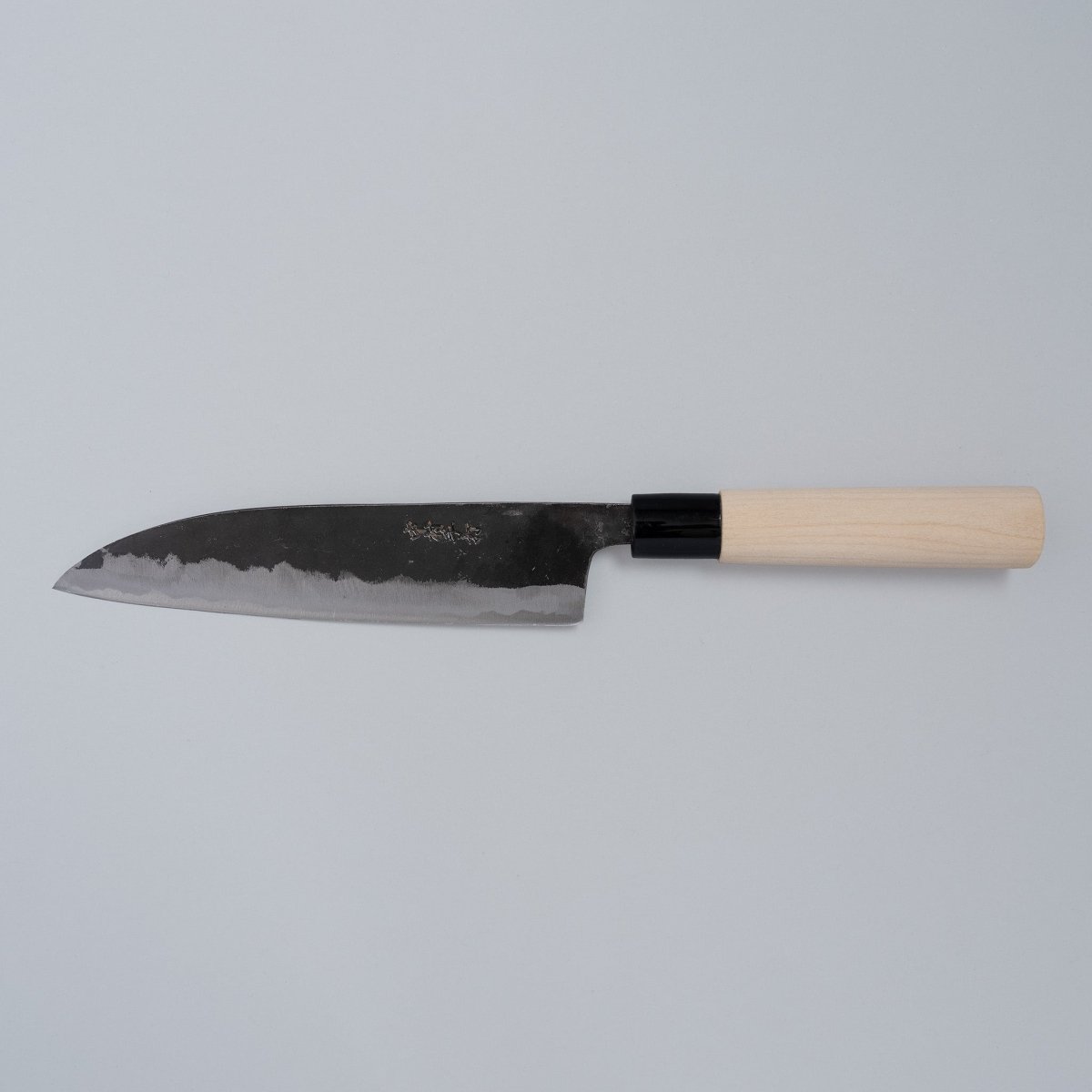 Kurouchi Santoku Knife 180mm crafted by Nakamura Blacksmith displayed horizontally on grey background