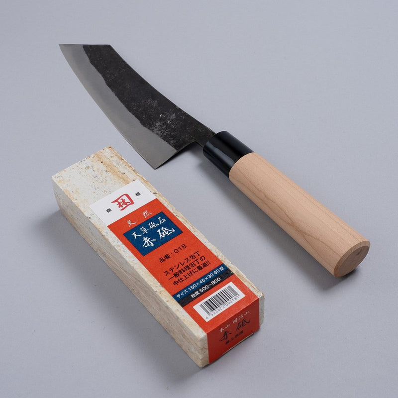 Nakamura Hamono Curved Back Bunka Kitchen Knife 165mm next to the free Amakusa red natural whetstone on a grey background