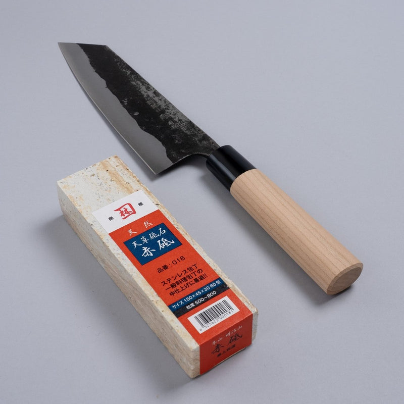 Nakamura Hamono Bunka Kitchen Knife 180mm next to the free Amakusa red natural whetstone on a grey background