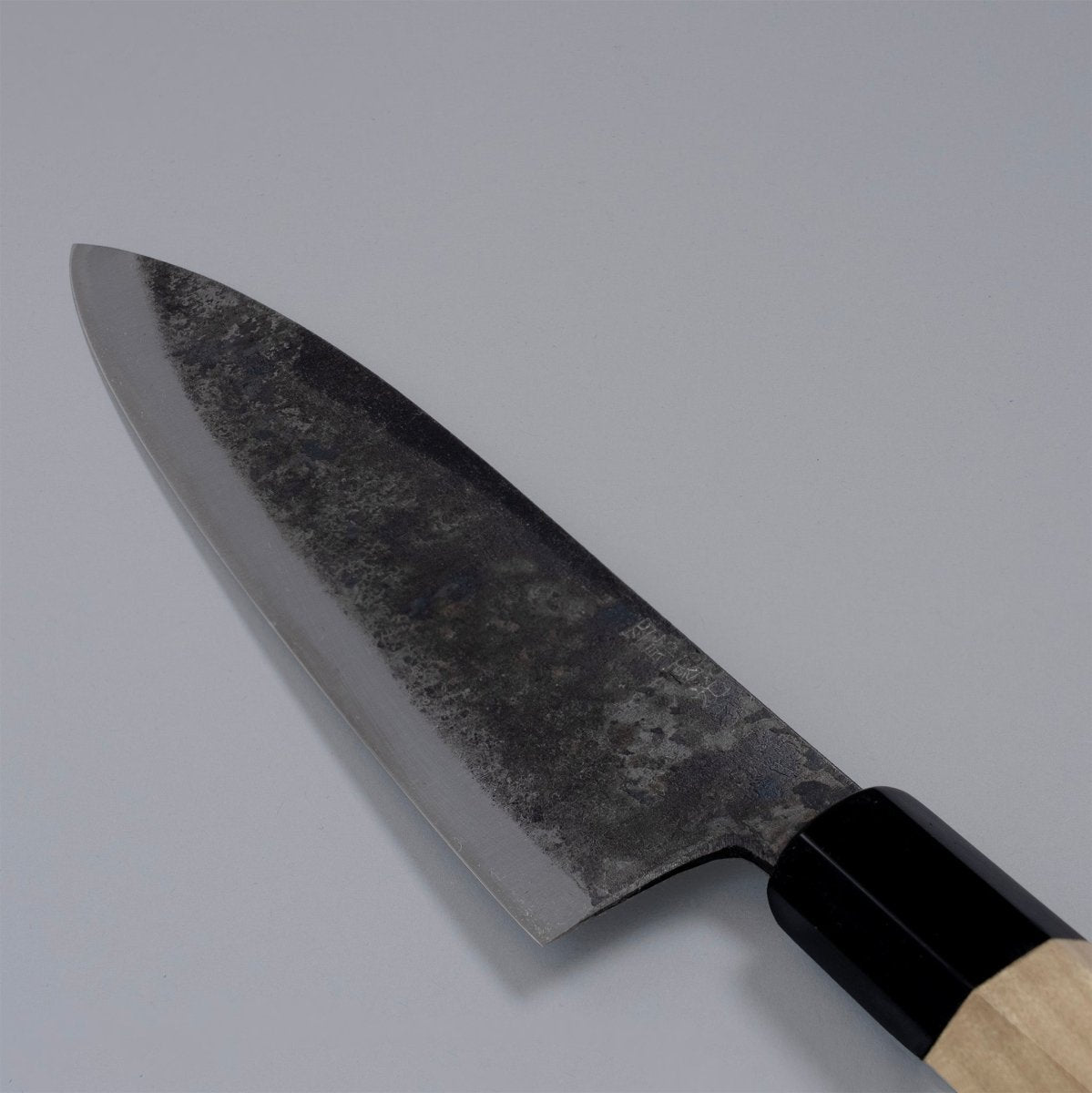 Closeup on blade of special Kurouchi Vegetable Funayuki Knife 170mm crafted by Shirou Kunimitsu on grey background