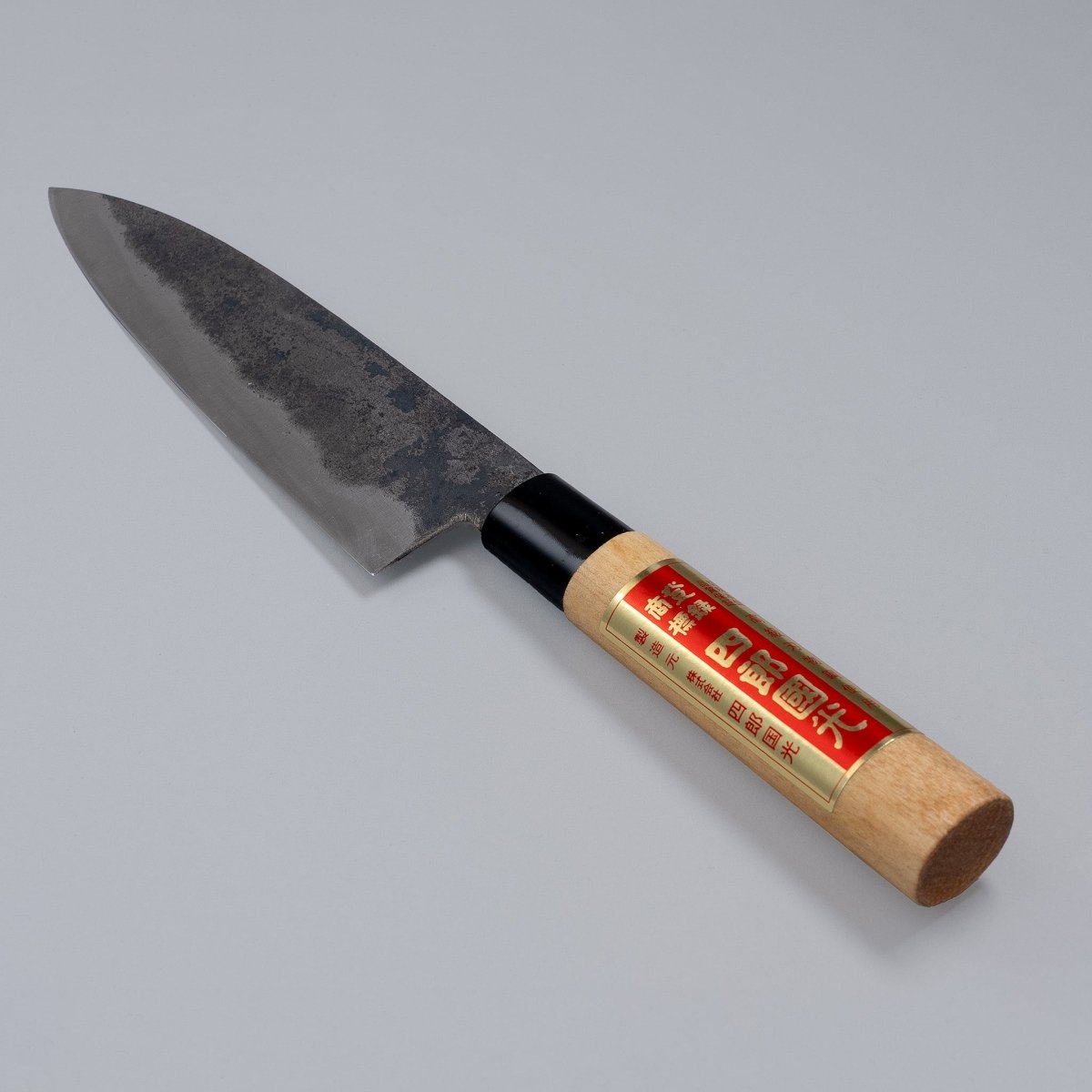 Single-Bevel Kurouchi Santoku Knife 170mm crafted by Shirou Kunimitsu displayed diagonally on grey background