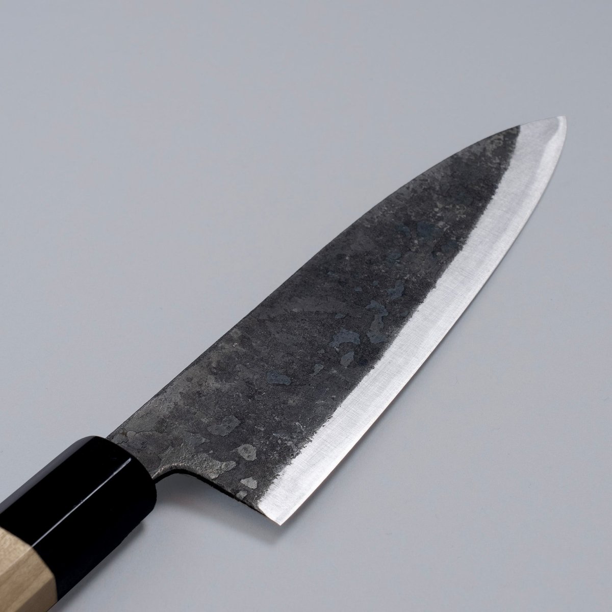 Closeup on reverse side of blade of special Kurouchi Vegetable Funayuki Knife 170mm crafted by Shirou Kunimitsu on grey background