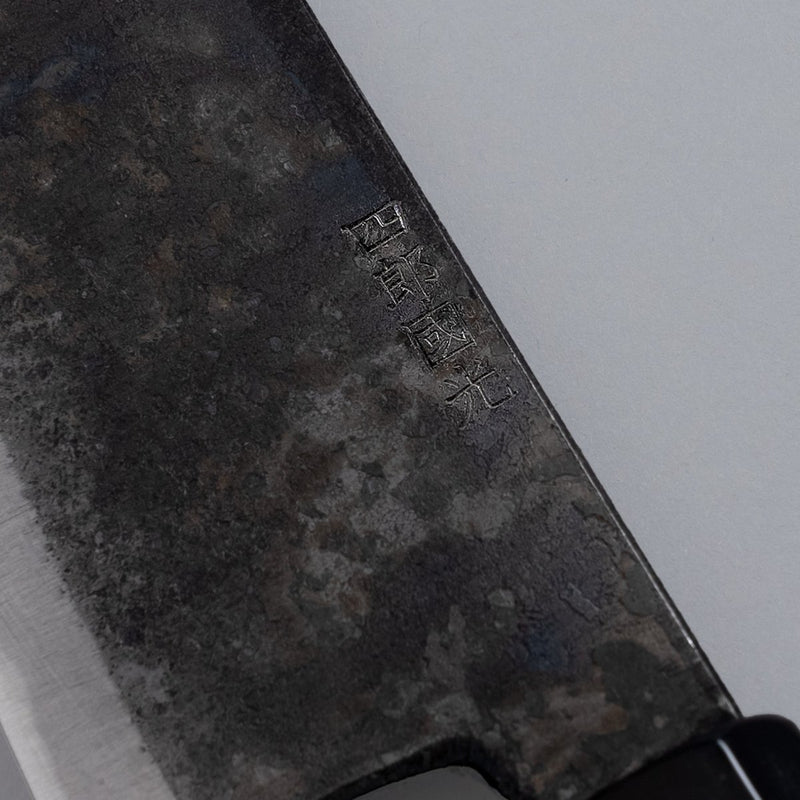 Closeup on engraving on single-Bevel Kurouchi Santoku Knife 170mm crafted by Shirou Kunimitsu on grey background