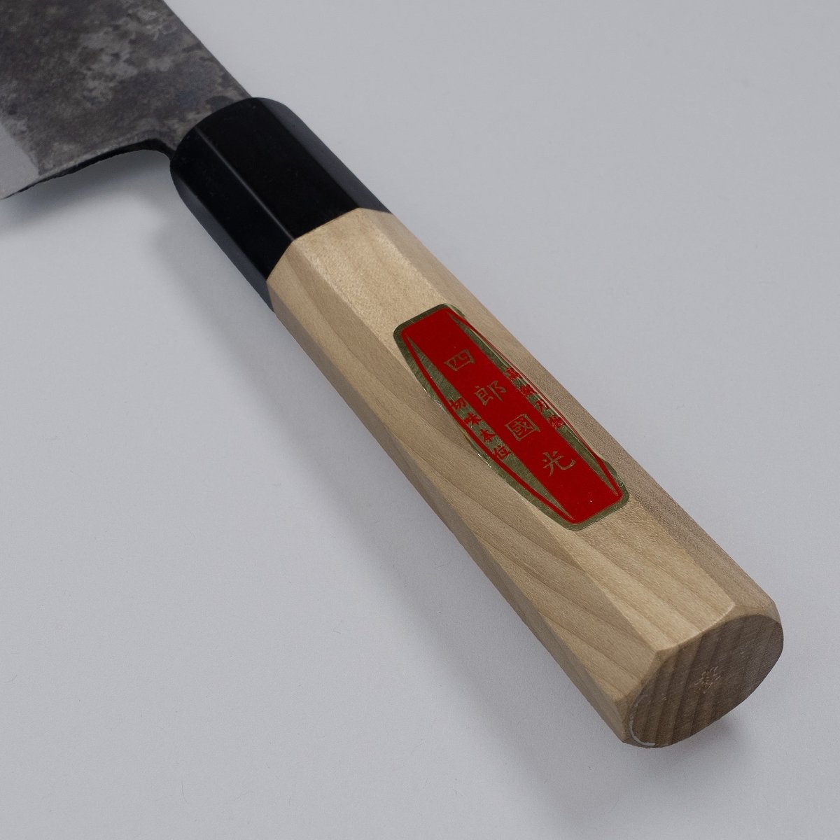 Closeup on handle of special Kurouchi Vegetable Funayuki Knife 170mm crafted by Shirou Kunimitsu on grey background