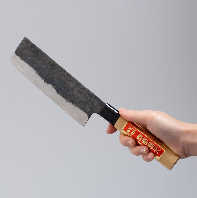 Hand holding single-Bevel Kurouchi Nakiri Knife 160mm crafted by Shirou Kunimitsu on grey background