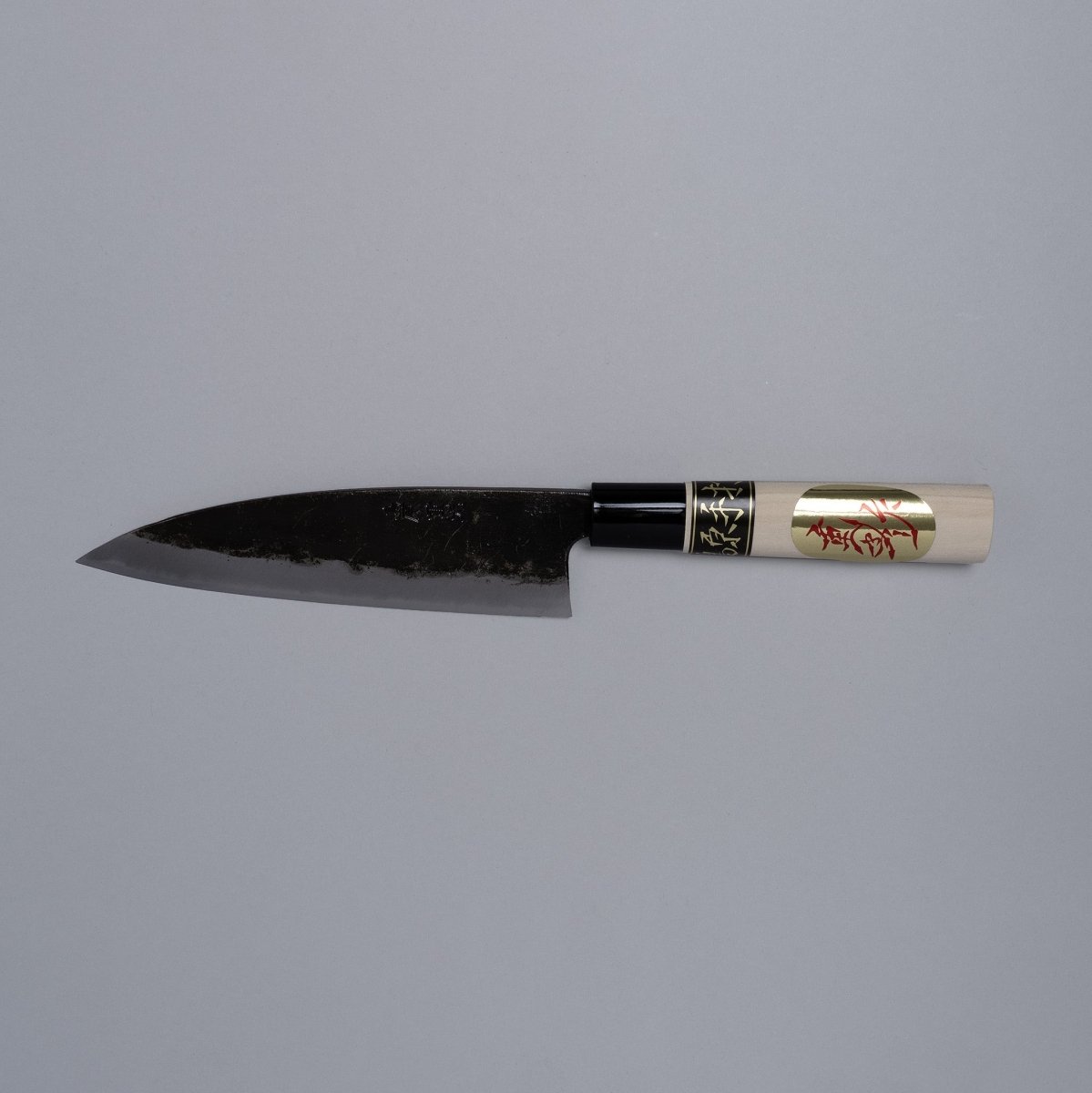 Kurouchi Deba knife 155mm crafted by Shigemitsu Hamono displayed horizontally on grey background 