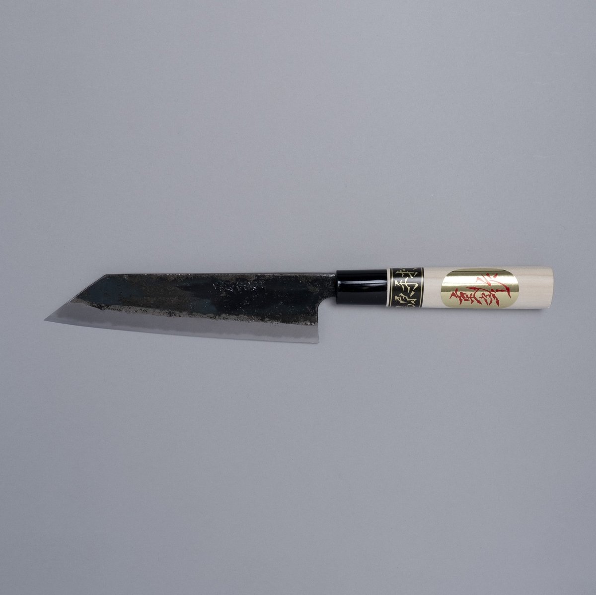 Kurouchi Santoku knife 160mm crafted by Shigemitsu Hamono displayed horizontally on grey background 