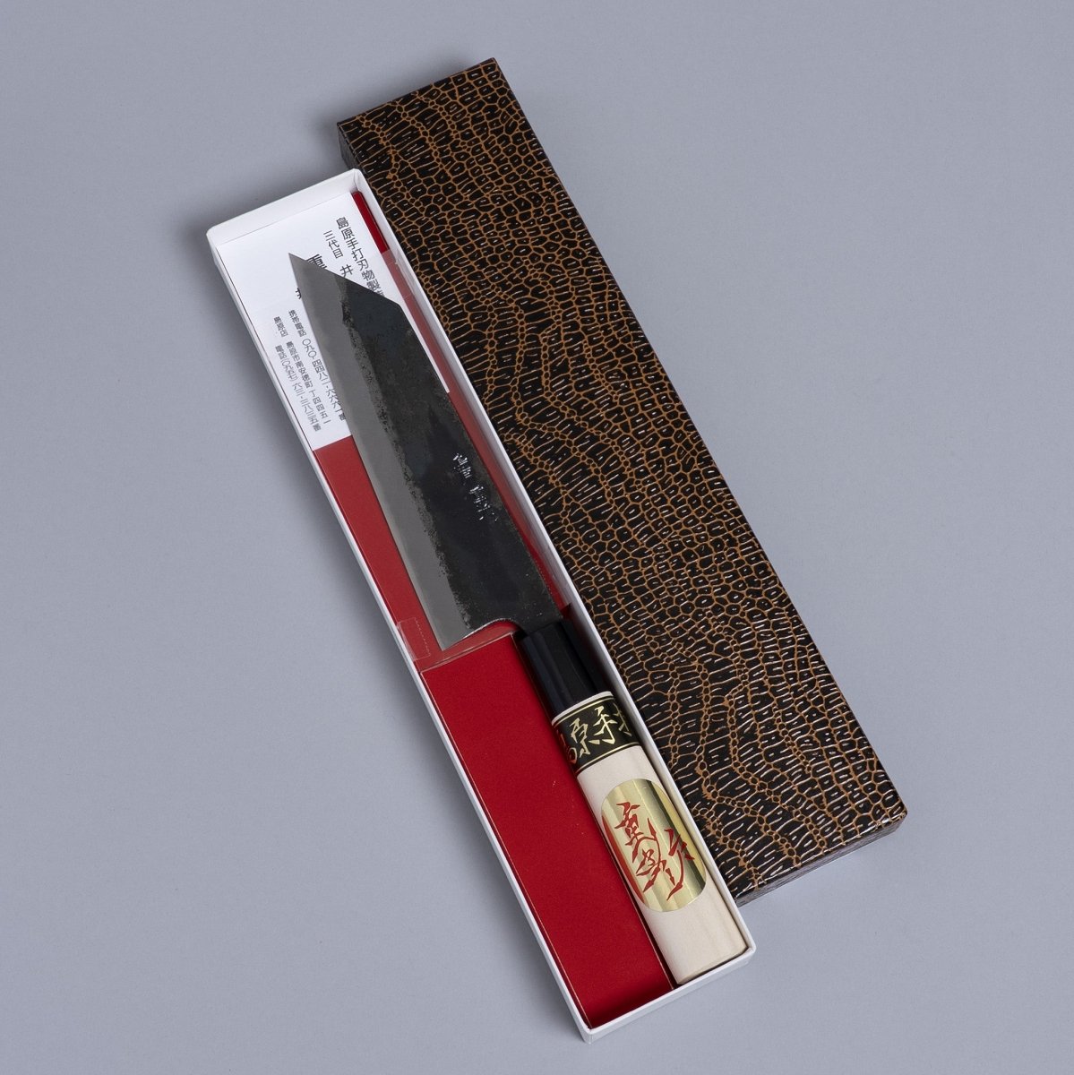 Kurouchi Santoku knife 160mm crafted by Shigemitsu Hamono in decorative box on grey background 