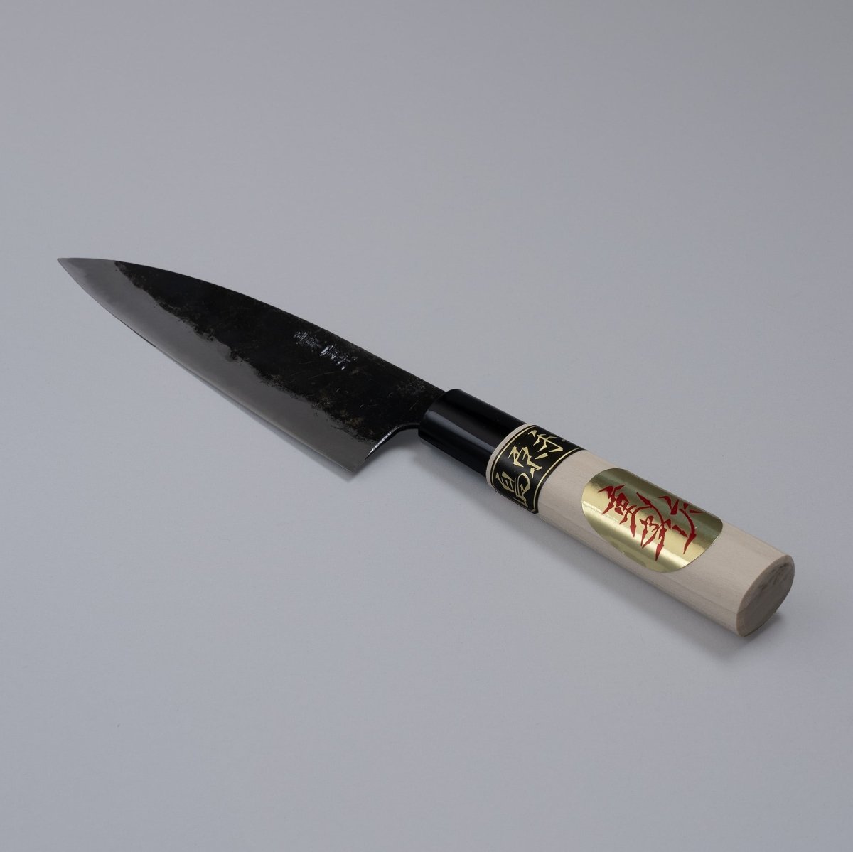 Kurouchi Deba knife 155mm crafted by Shigemitsu Hamono displayed diagonally on grey background 