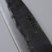 Closeup on engraving on blade of Kurouchi Deba knife 155mm crafted by Shigemitsu Hamono on grey background 
