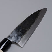 Closeup on blade of Kurouchi Deba knife 155mm crafted by Shigemitsu Hamono displayed diagonally on grey background 