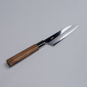 Ginsan stainless Petty knife 135mm crafted by Kurotori Blacksmith displayed diagonally on grey background
