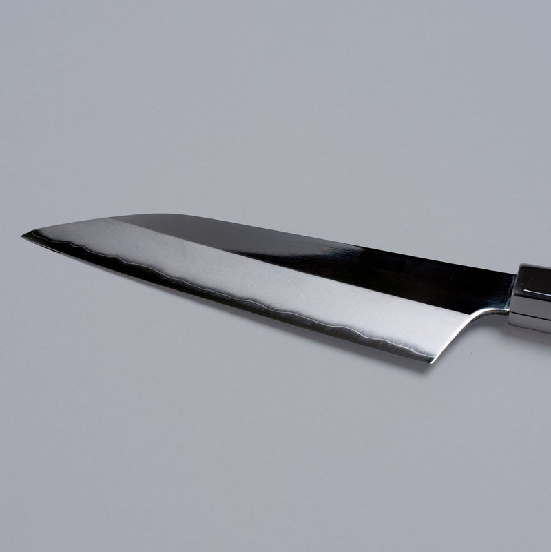 Closeup on reverse side of blade of ginsan stainless Petty knife 135mm crafted by Kurotori Blacksmith on grey background