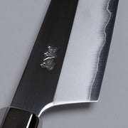 Closeup on engraving on ginsan stainless Petty knife 135mm crafted by Kurotori Blacksmith on grey background