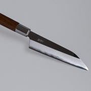 Closeup on tip of ginsan stainless Petty knife 135mm crafted by Kurotori Blacksmith on grey background