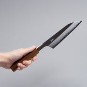 Hand holding ginsan stainless Petty knife 135mm crafted by Kurotori Blacksmith on grey background