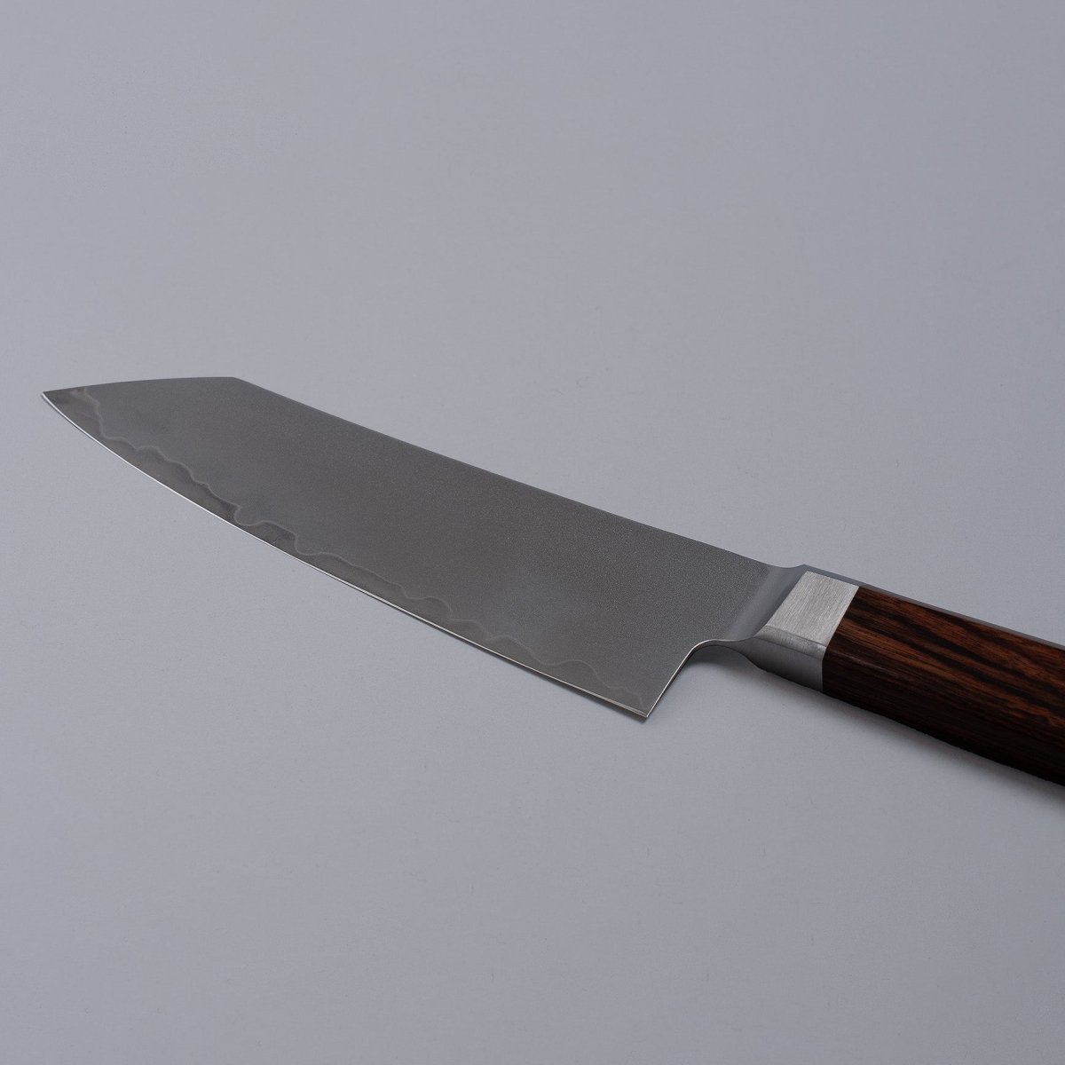 Closeup on reverse side of blade of VG-10 stainless steel KIRINAMI Kiritsuke Bunka 150mm crafted by Seki Kikusui Cutlery on grey background