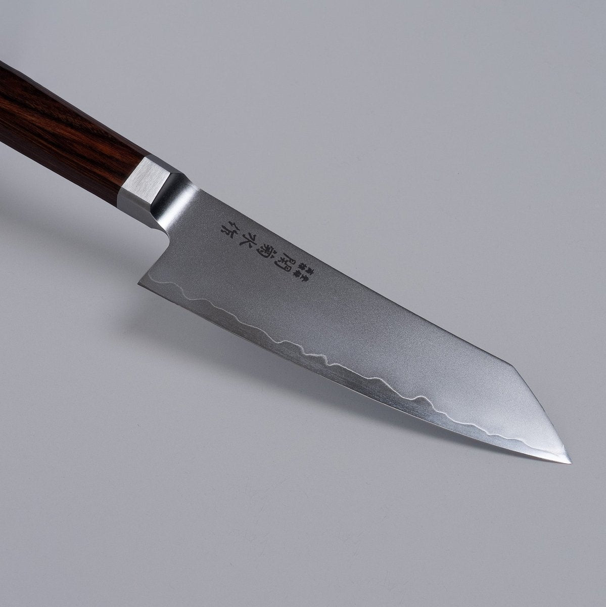 Closeup on tip of VG-10 stainless steel KIRINAMI Kiritsuke Bunka 150mm crafted by Seki Kikusui Cutlery on grey background