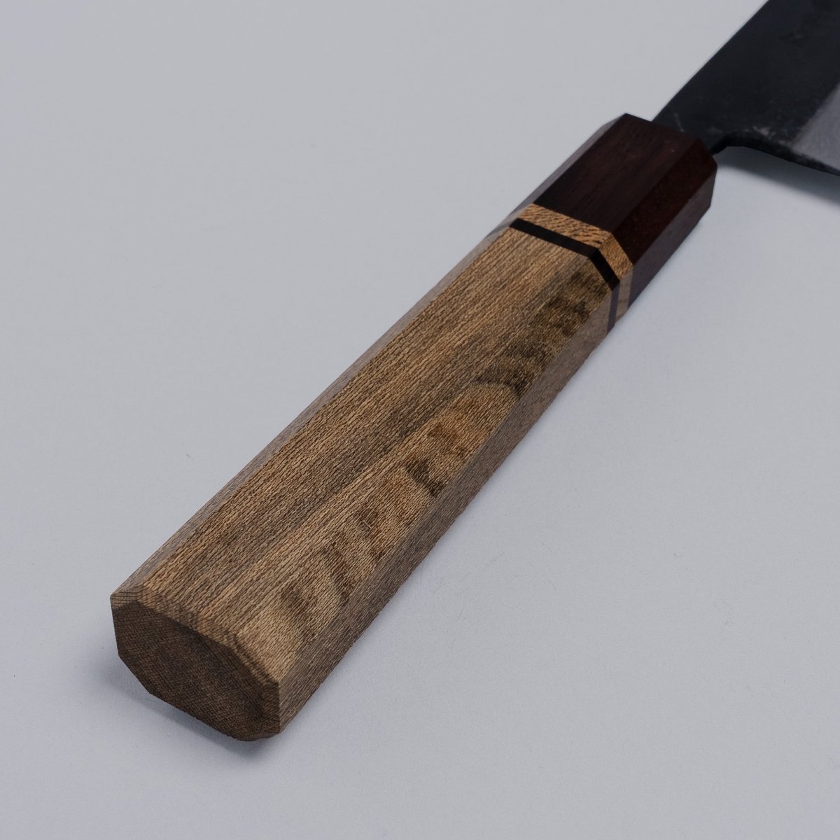 Closeup on handle of Kurouchi Damascus Blue Steel No. 2 Kiritsuke 210mm by Kajihara Hamono on grey background