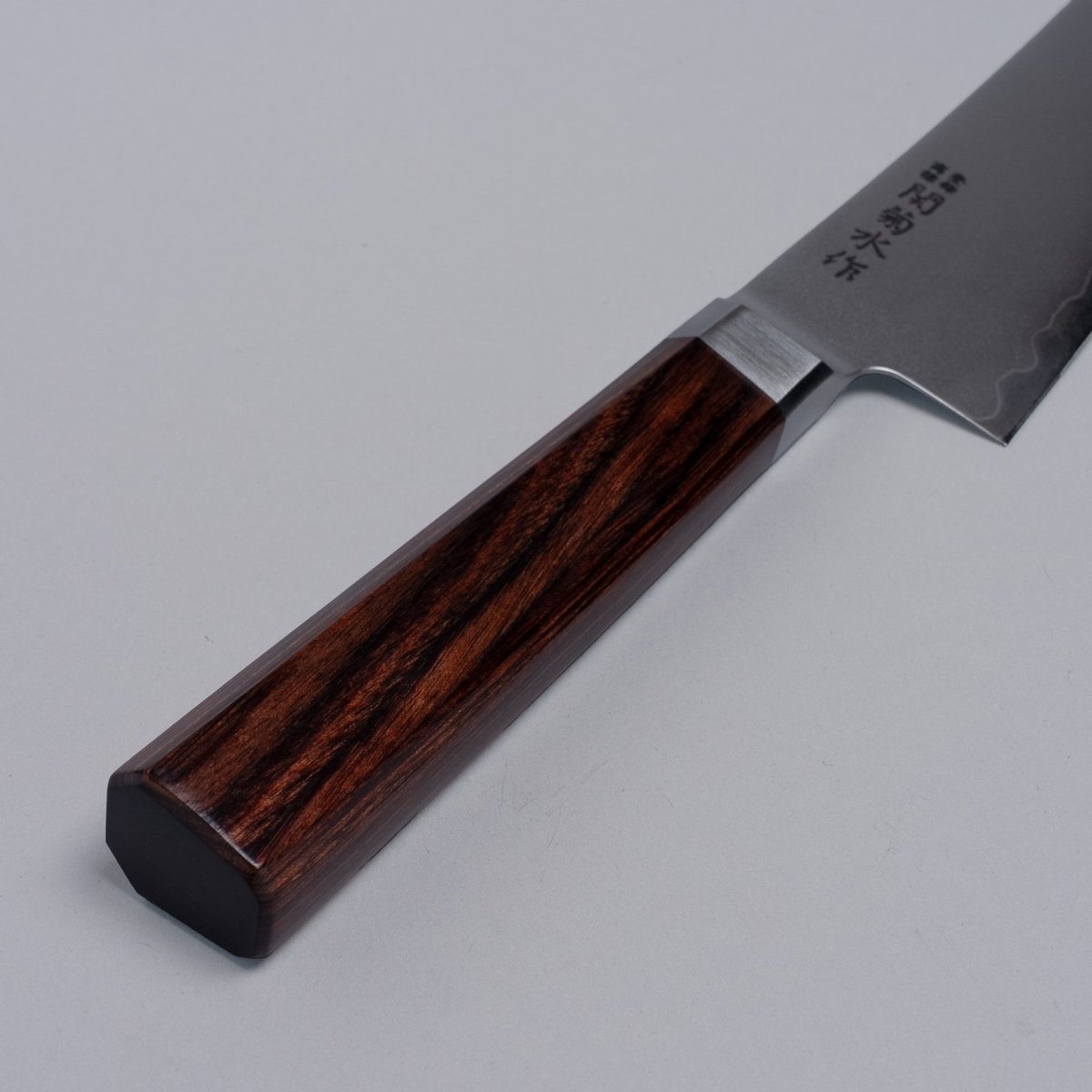 Closeup on handle of VG-10 stainless steel KIRINAMI Kiritsuke Bunka 150mm crafted by Seki Kikusui Cutlery on grey background