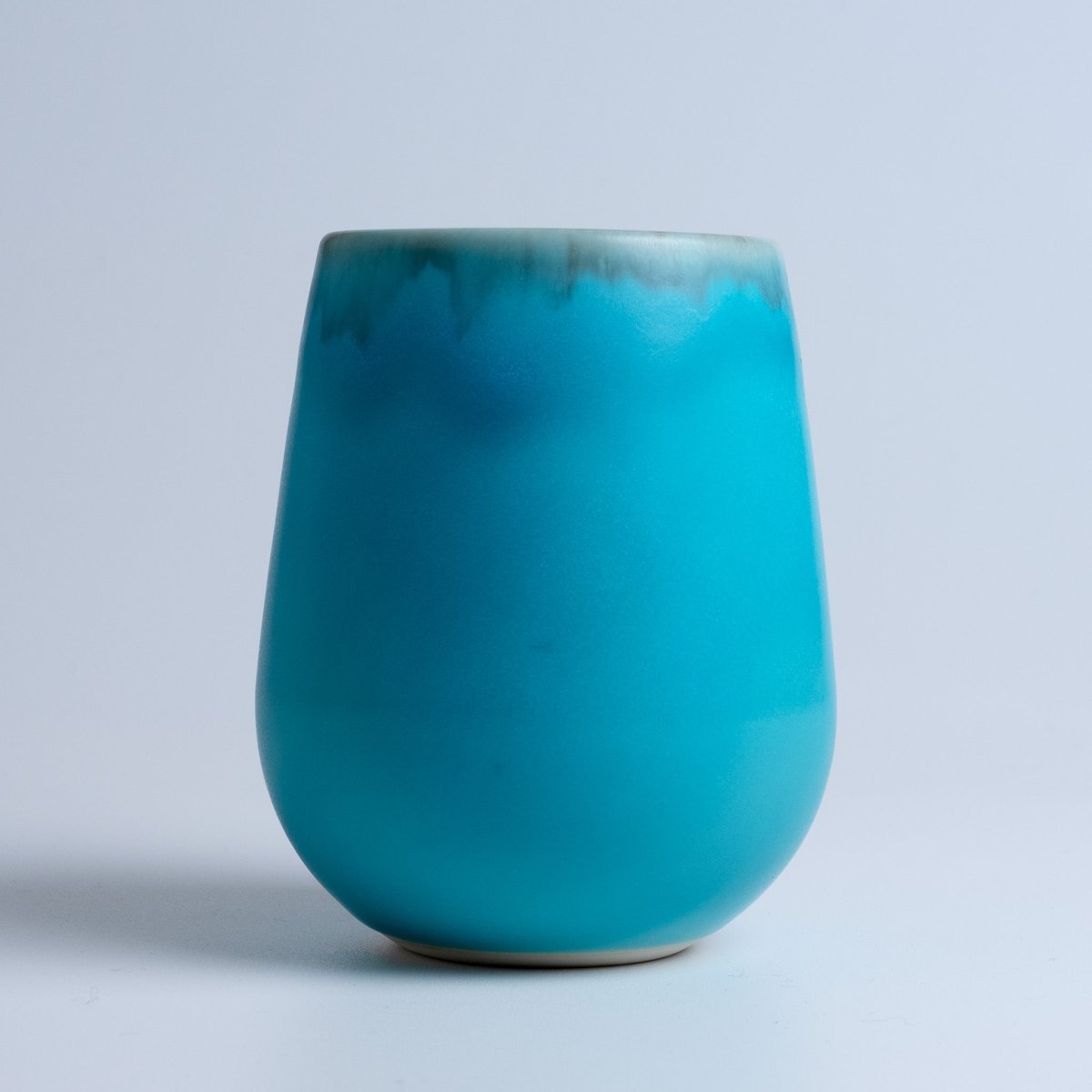 Closeup of the side of a Round Porcelain Cup in turquoise blue by Imari Togei