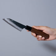 Hand holding a Nishida Hamono Kurouchi Petty Knife 100mm